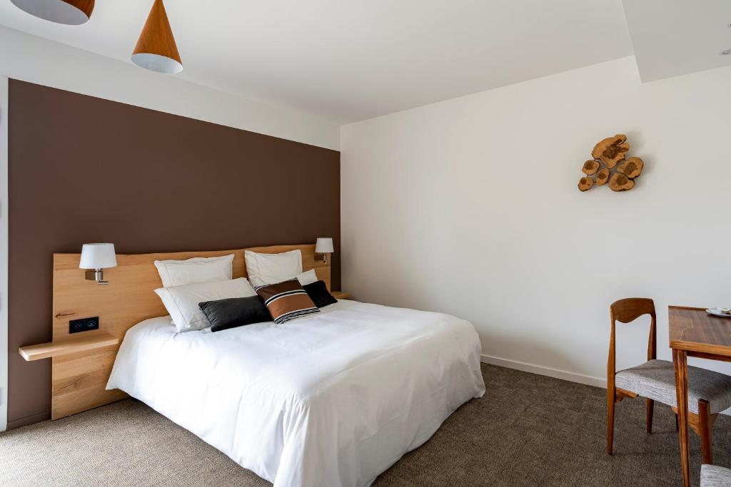 Schlafzimmer mit einem großen weißen Bett und einem Schreibtisch in der Unterkunft HOTEL LE 25 in Andernos-les-Bains