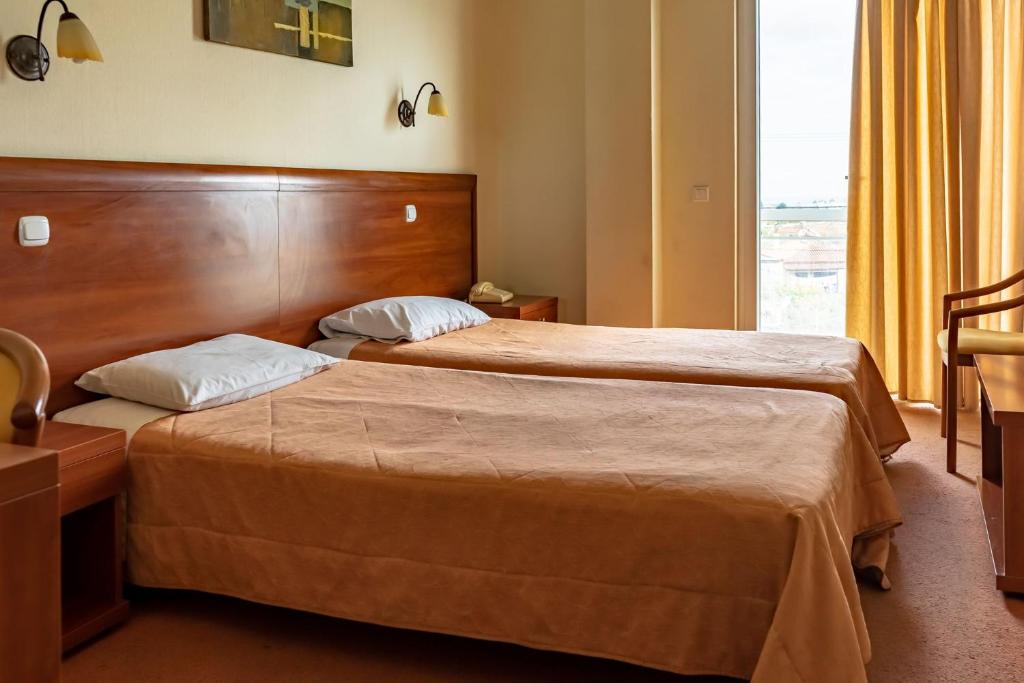 a hotel room with two beds and a window at Telis Hotel in Aigio