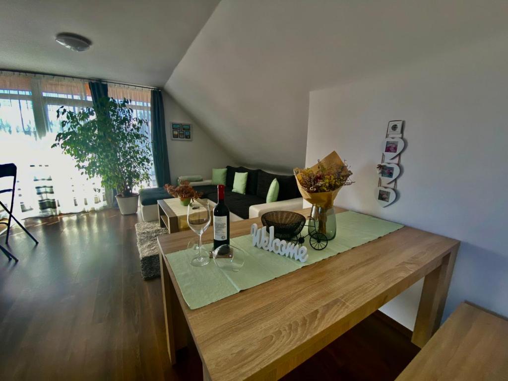 バラトンフェニヴェシュにあるMunkácsy Apartmanokのリビングルーム(木製テーブル、ワイングラス付)