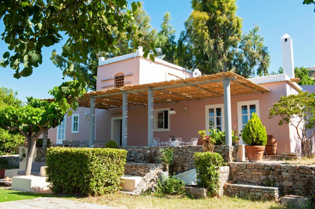 a pink house with a stone wall and trees at Montofoli Wine Estate in Karistos