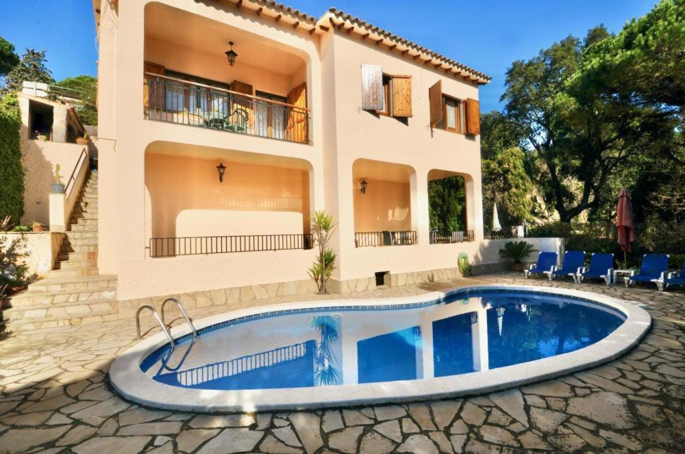 eine Villa mit einem Pool vor einem Haus in der Unterkunft Villa Victoria in Lloret de Mar