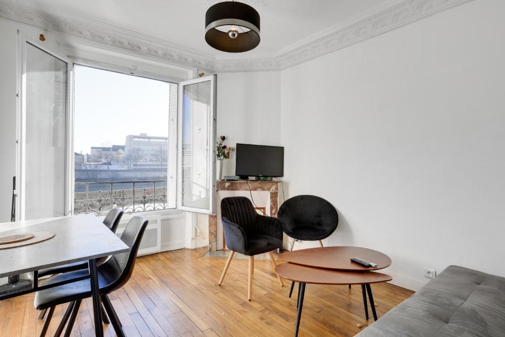 un soggiorno con divano, tavolo e sedie di Appartement meublé quai de Seine a Ivry-sur-Seine