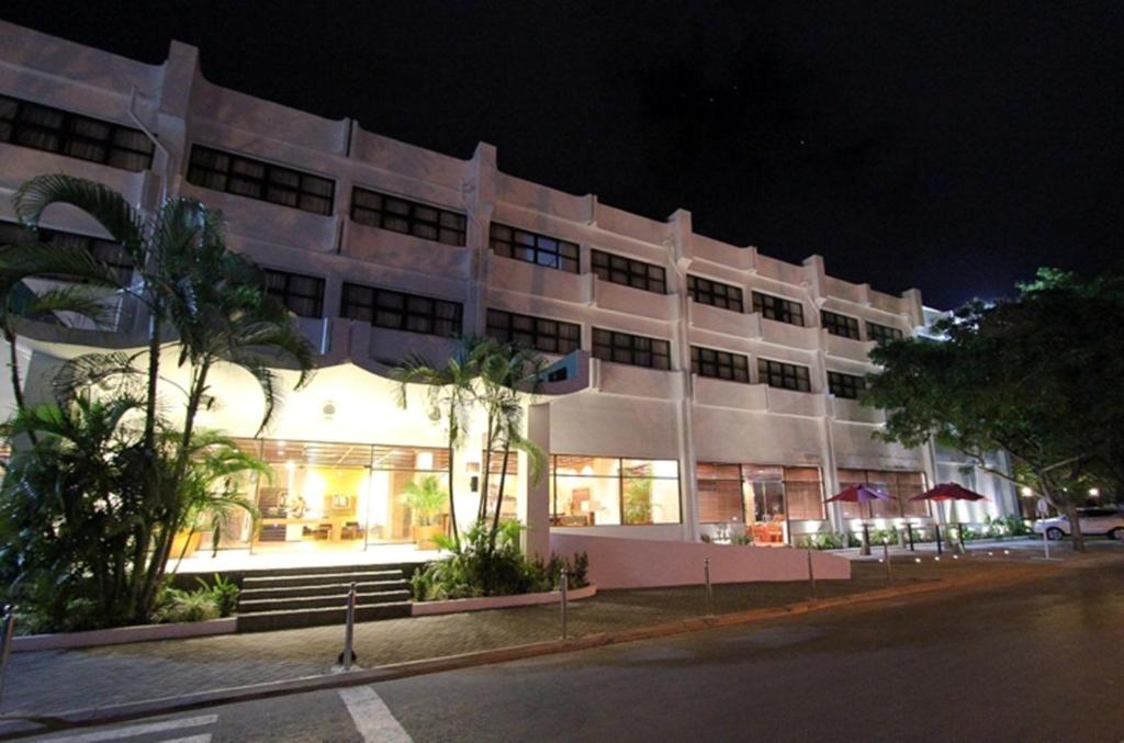 a large white building at night with a street at Hotel Timor in Dili