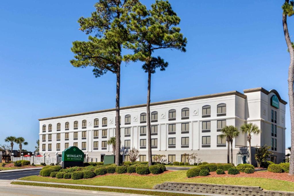 a white building with palm trees in front of it at Wingate by Wyndham Wilmington in Wilmington