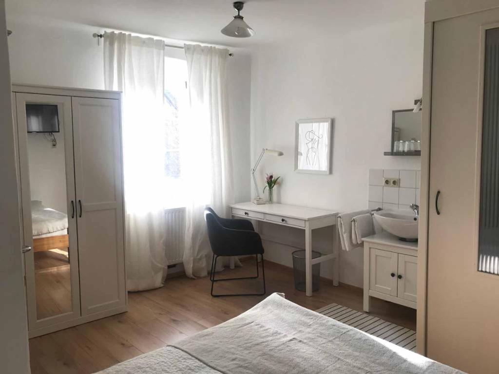 um quarto branco com uma secretária, um lavatório e uma janela em Gästehaus Lurger em Krems an der Donau