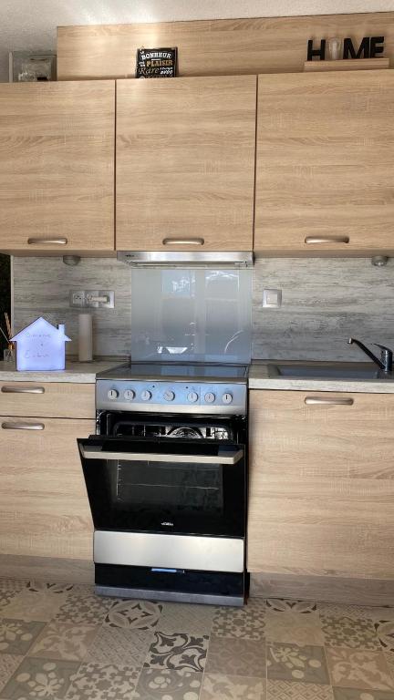 a stove top oven in a kitchen with wooden cabinets at Embrun - Appartement 4&#47;6 personnes avec extérieurs in Embrun