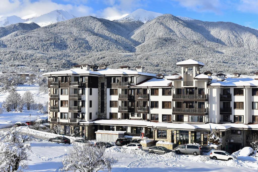 a hotel in the snow with mountains in the background at St George Ski & Holiday - Half Board & All Inclusive in Bansko