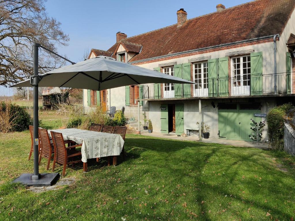 a table with an umbrella in front of a house at Chambres d'hôtes / B&B Chez Mon Rêve in Éguzon-Chantôme