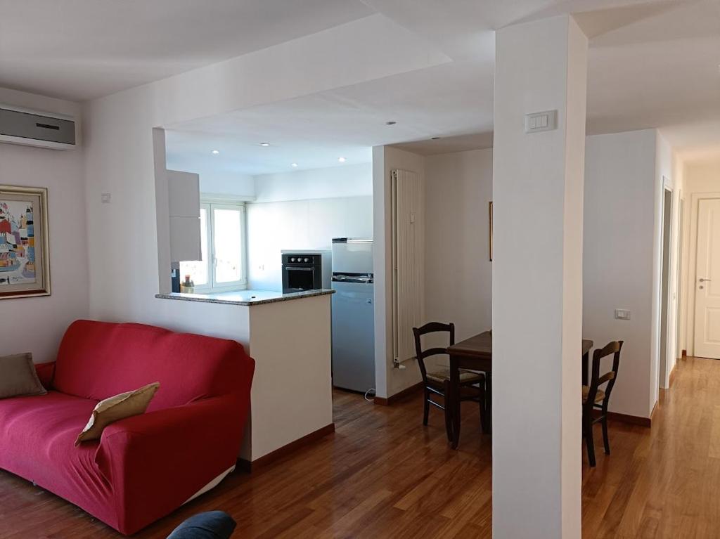 salon z czerwoną kanapą i kuchnią w obiekcie Gloriapartment w mieście Civitavecchia