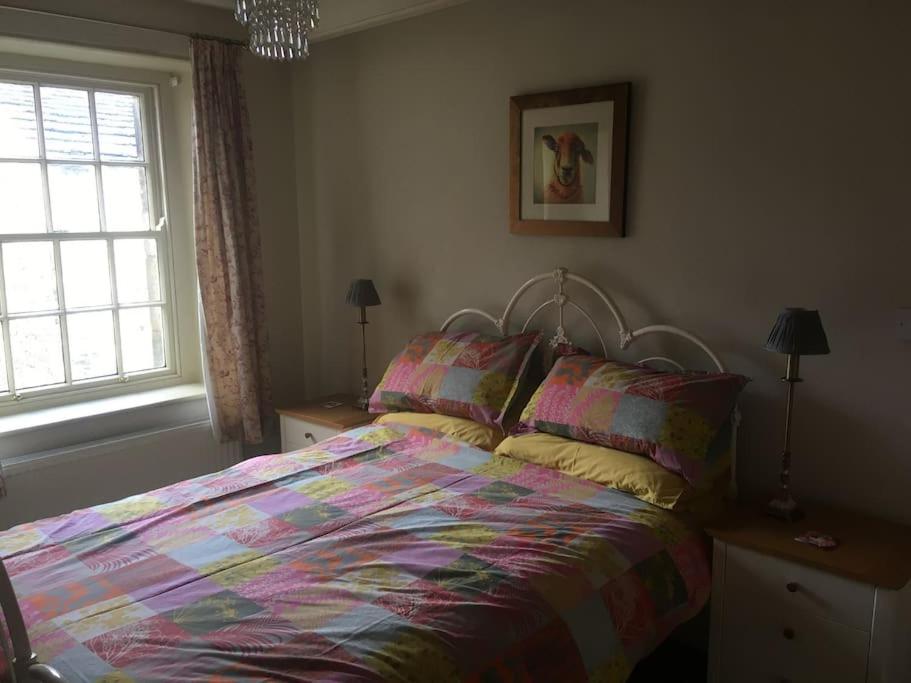 - une chambre avec un lit doté d'une couette colorée et 2 fenêtres dans l'établissement Rustic cottage, garden, near amenities, wifi, à Pateley Bridge