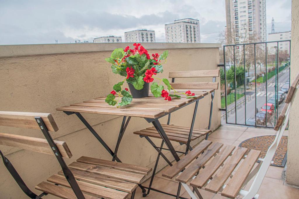 una mesa de madera con flores rojas en el balcón en Apartment Villeneuve Stade de France Free parking WiFi, en Villeneuve-la-Garenne