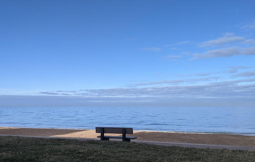 a bench sitting on the grass near the ocean at Seashore Hideaway studio in Hermanville-sur-Mer