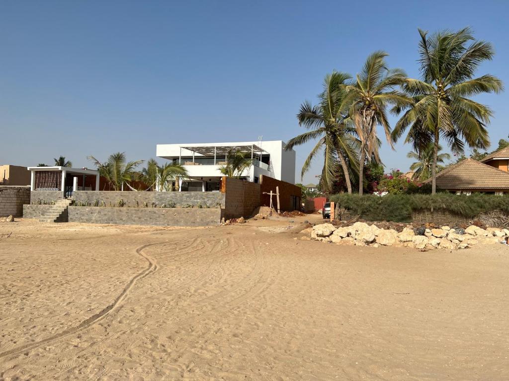 una playa de arena con palmeras y un edificio en beachhouse MIMA, en Saly Portudal