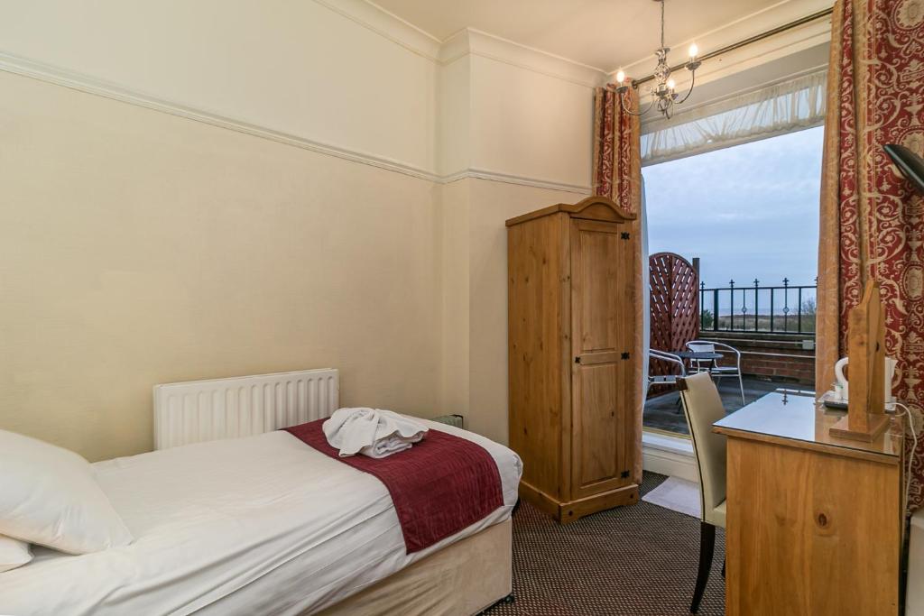 um quarto com uma cama, uma secretária e uma janela em The Royal Hotel em Skegness