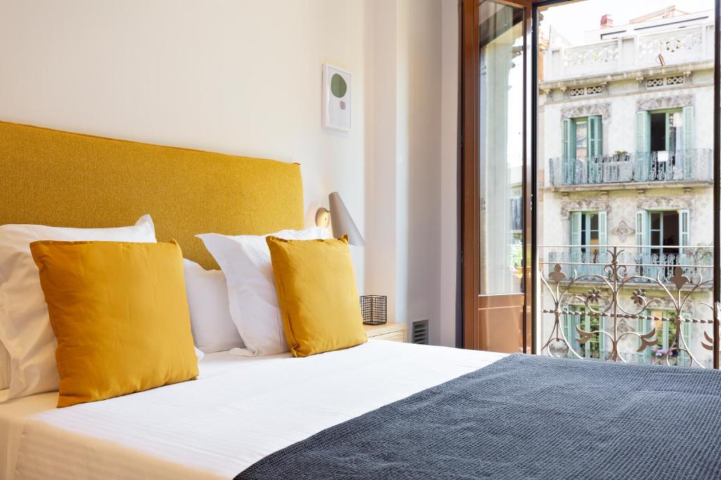 Un dormitorio con una cama con almohadas amarillas y una ventana en Central Apartments Barcelona, en Barcelona