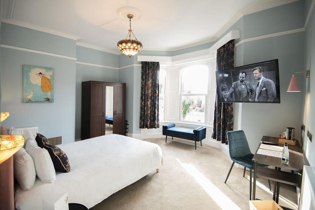 um quarto com uma grande cama branca e uma secretária em The Elizabeth House Hotel em Southampton