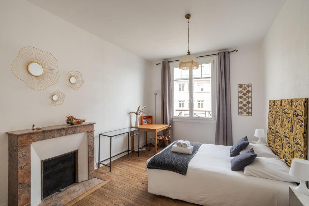 een woonkamer met een bed en een open haard bij DUCHESSE - Appartement cosy en cœur de ville in Rennes