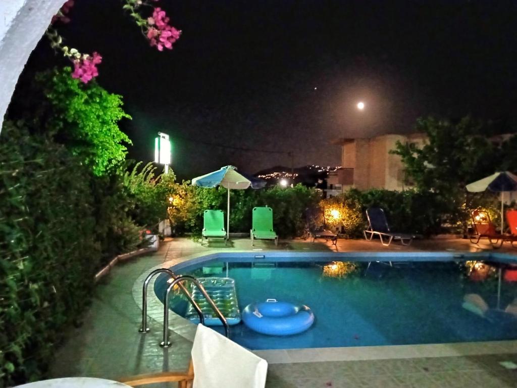 una piscina notturna con sedie e tavoli di Creta Sun Hotel Studios ad Agia Pelagia
