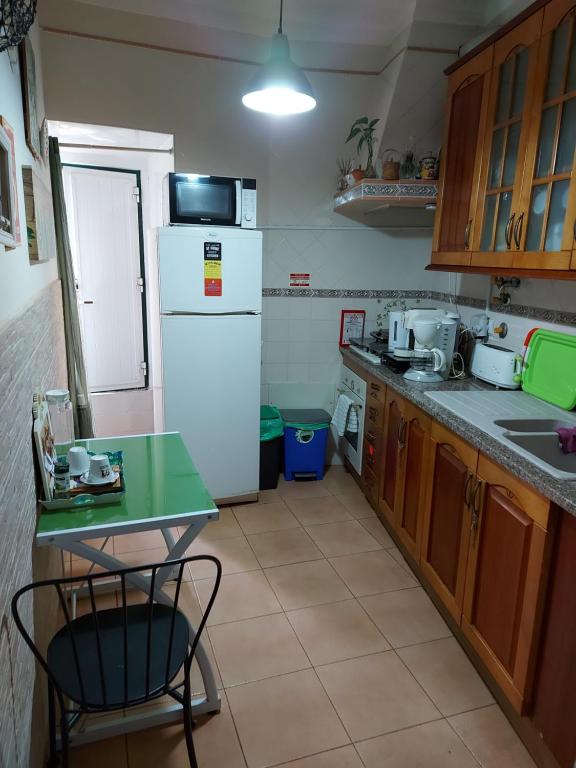 
a kitchen with a refrigerator, stove, sink and microwave at Guest House Capitao Mor in Faro
