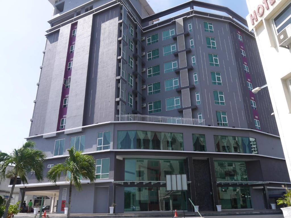 un alto edificio gris con palmeras delante en MidCity Hotel Melaka, en Melaka