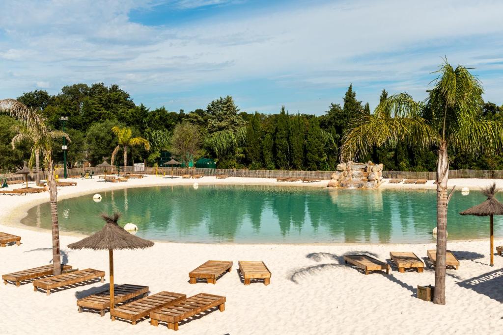 uma piscina com cadeiras e guarda-sóis numa praia em Camping maeva Club Le Lagon d'Argelès em Argelès-sur-Mer