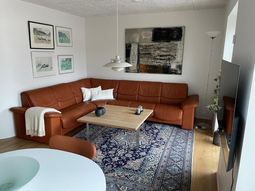 a living room with a brown couch and a coffee table at Nice modern apartment in Tórshavn