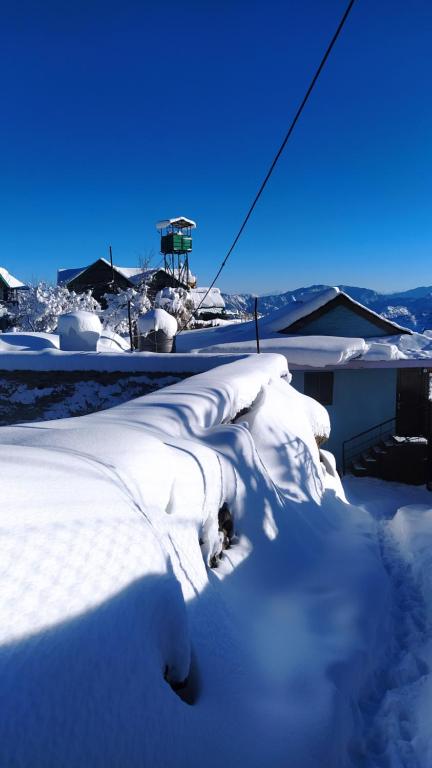 a pile of snow on the side of a house at Deodar Homestay Dakbangla-kufri in Shimla