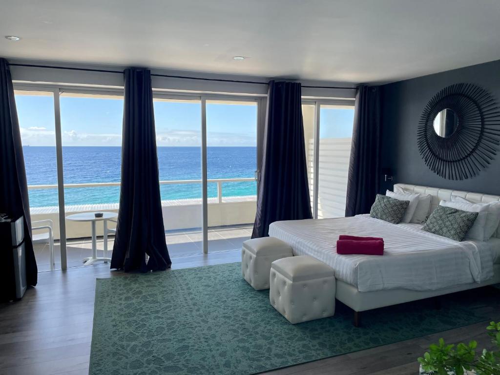 een slaapkamer met een bed en uitzicht op de oceaan bij Saint Tropez Boutique Hotel in Willemstad