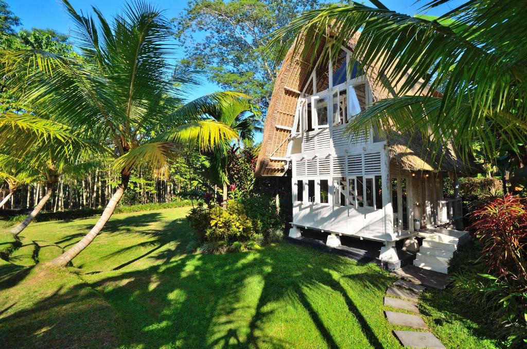 a white house with palm trees in front of it at Jendela Di Bali Villa in Tegalalang