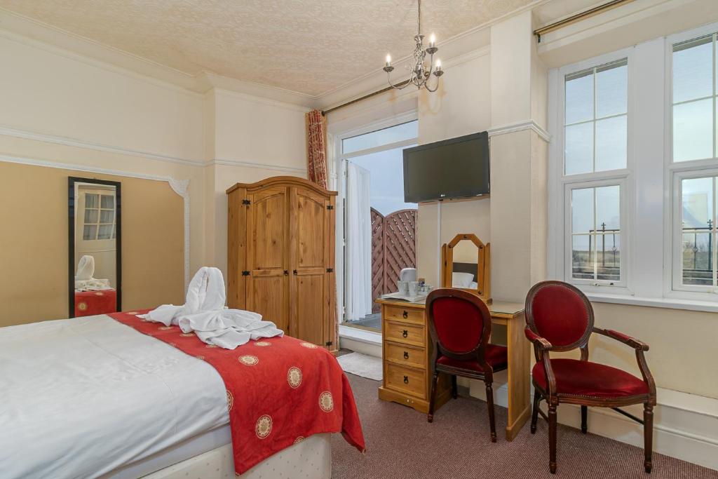 a bedroom with a bed and a desk and two chairs at Skegness The Royal Hotel in Skegness