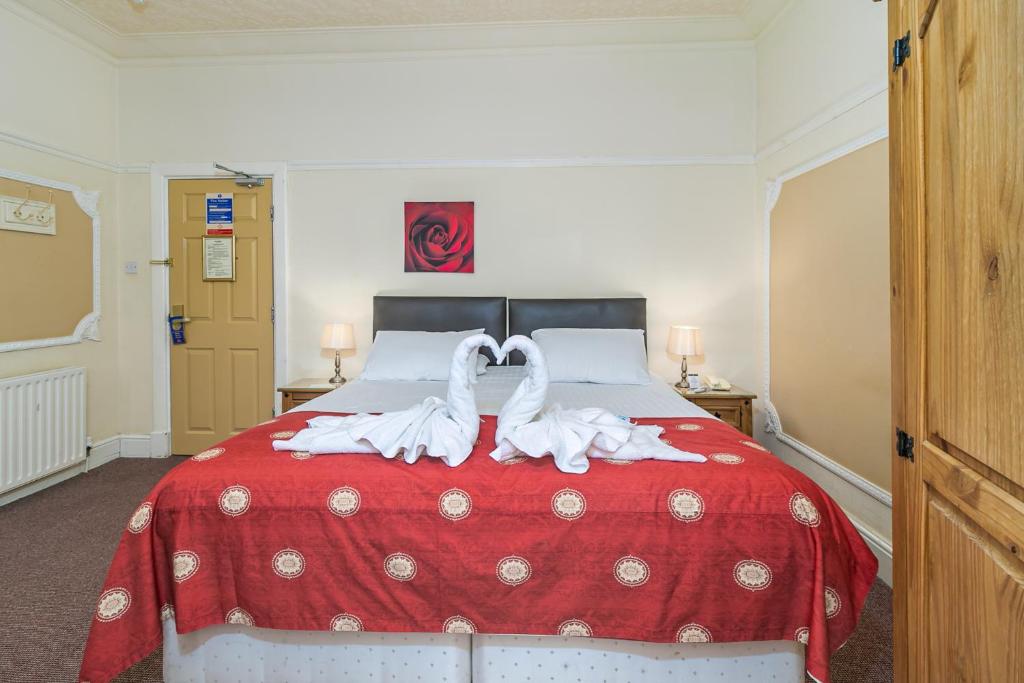 a bedroom with a red bed with towels on it at Skegness The Royal Hotel in Skegness