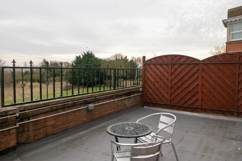 a patio with two chairs and a table and a fence at Skegness The Royal Hotel in Skegness