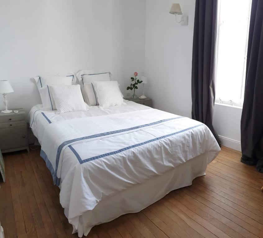 een wit bed met witte lakens en kussens in een slaapkamer bij La Joséphine in Cosne Cours sur Loire