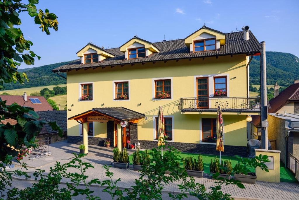 a large yellow house with a gambrel roof at Penzión Pod Babou in Omšenie