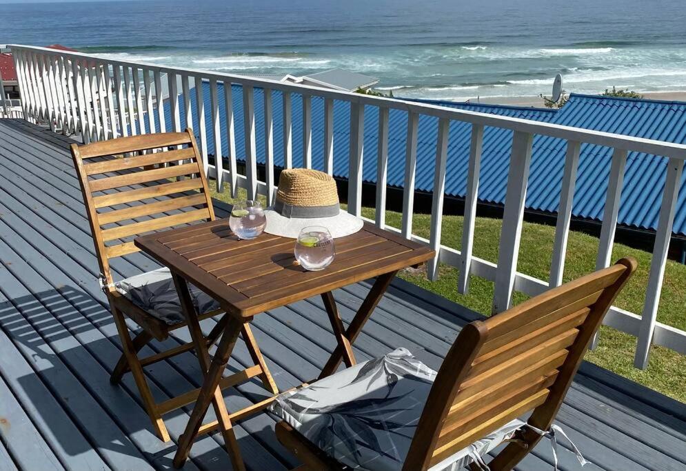 - une table en bois et 2 chaises sur une terrasse donnant sur l'océan dans l'établissement TAKE TWO lovely beach apartment, Great Brak River, à Groot Brakrivier