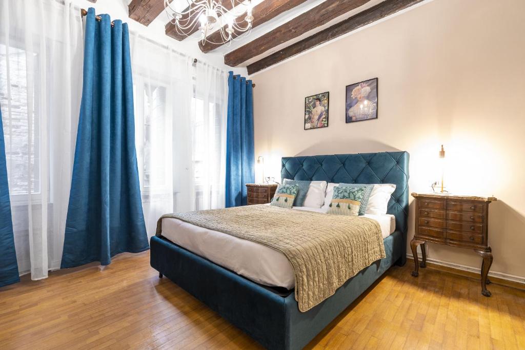 Schlafzimmer mit blauem Bett und blauen Vorhängen in der Unterkunft Ca Maurice - San Marco Canal view in Venedig