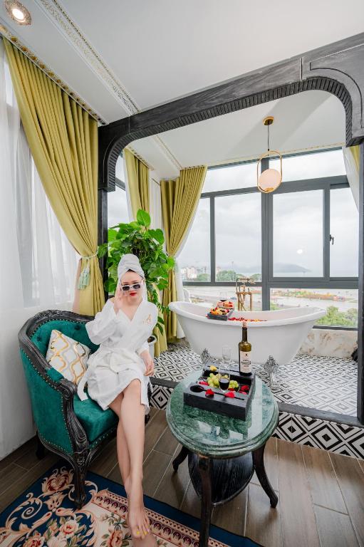 a woman sitting in a chair in a bathroom with a tub at Athena Hotel Quy Nhơn in Quy Nhon