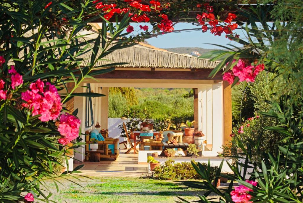 un giardino con pergolato e fiori rosa di Alba B&B a Carloforte