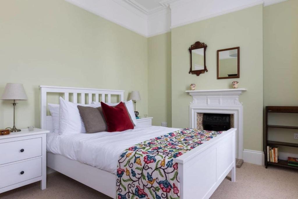 a bedroom with a white bed and a fireplace at Impressive 5BR family home in Leafy in London