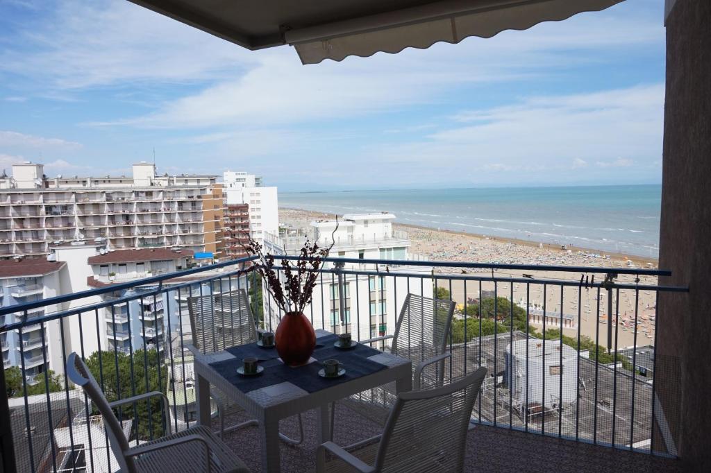 een balkon met een tafel en stoelen en uitzicht op het strand bij Beautiful Studio with sea view in Lignano Sabbiadoro