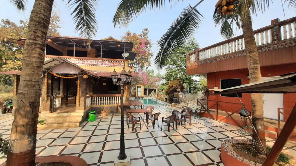 a patio with tables and chairs in front of a house at Alibaug Sunside Villa 3BHK Near Beach in Alibaug