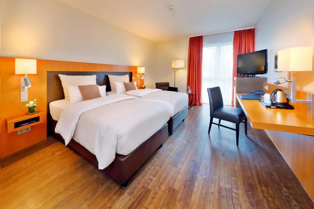 una grande camera da letto con un grande letto e una scrivania di Best Western Premier IB Hotel Friedberger Warte a Francoforte sul Meno