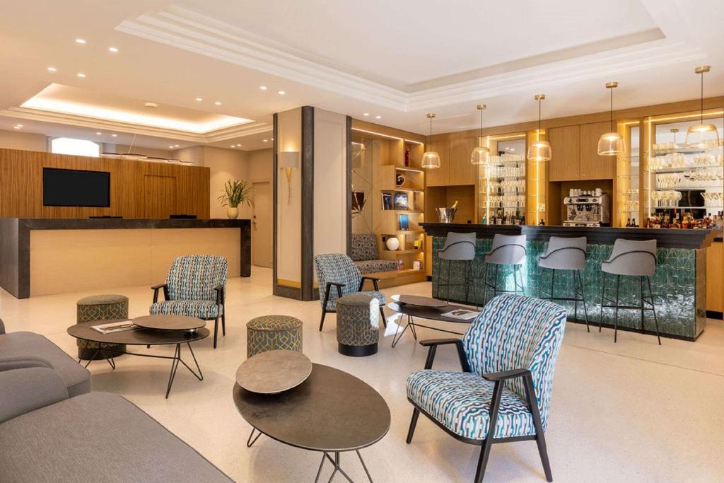 a lobby with chairs and tables and a bar at Hôtel Apollinaire Nice in Nice