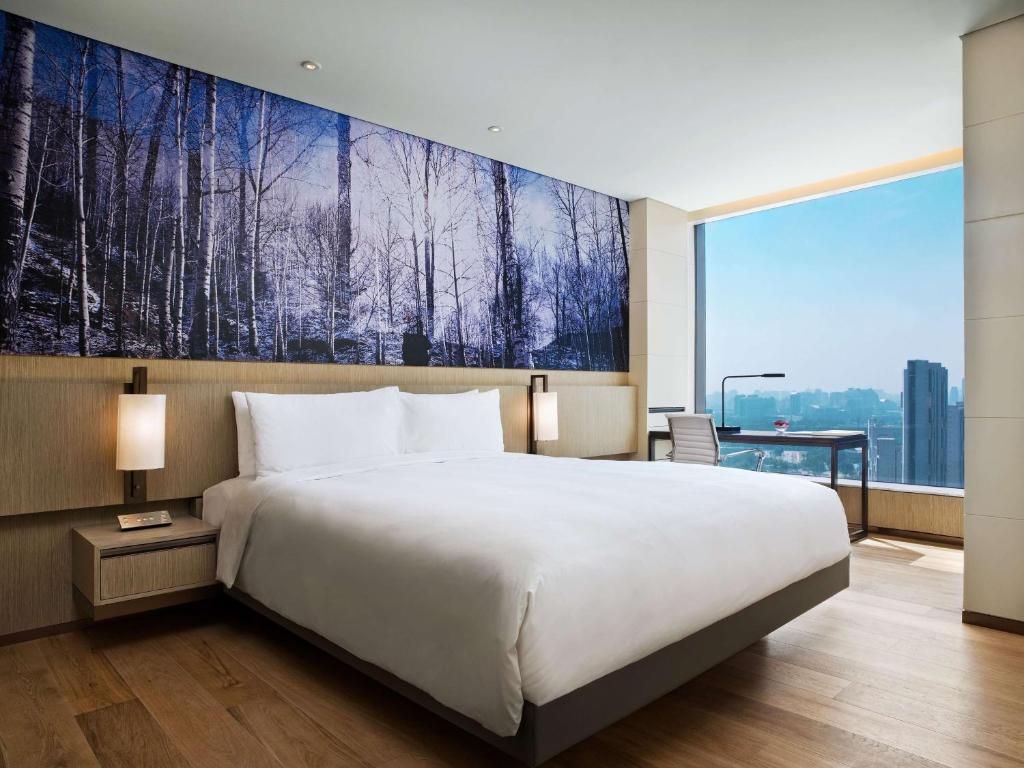 a hotel room with a large bed and a painting on the wall at East Beijing in Beijing