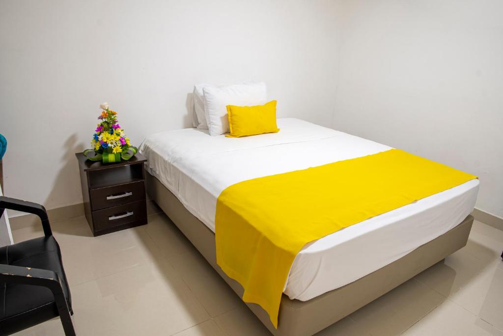 a bedroom with a bed with a yellow blanket on it at Hotel ITACO in Cartagena de Indias