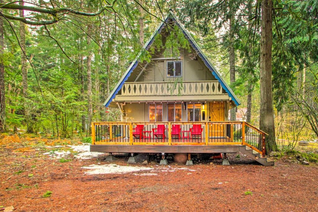a house with red chairs in the woods at Cozy A-Frame with Hot Tub, Fire Pit, and Fireplace! in Packwood