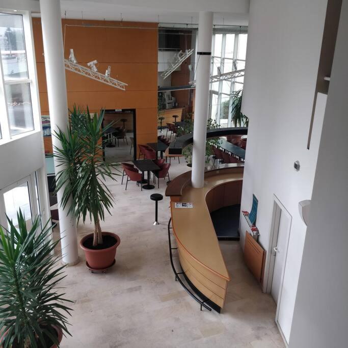 un hall avec un bureau et des plantes dans un bâtiment dans l'établissement Direct Aéroport et centre historique de Bordeaux, à Mérignac