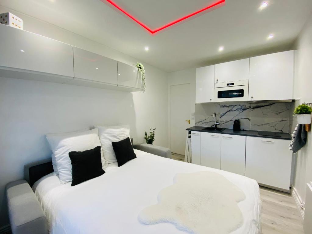 Cet appartement comprend une chambre avec un lit blanc et une cuisine. dans l'établissement Le petit écrin de Deauville, à Deauville