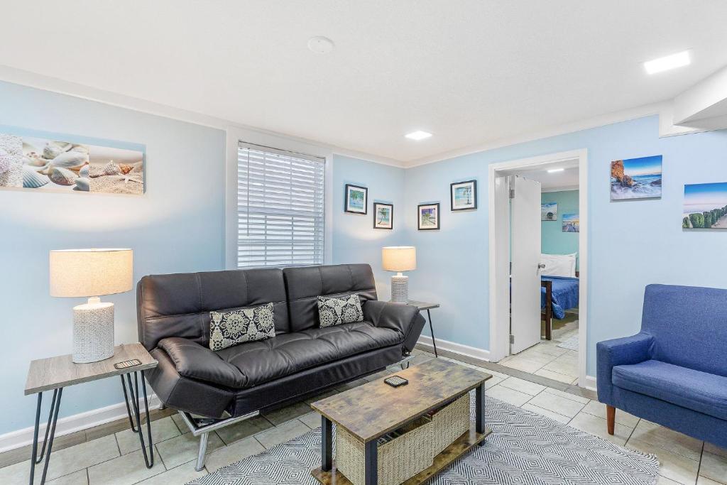 uma sala de estar com um sofá de couro e uma cadeira azul em 23 Center St - Sunny Side Down - Downstairs Apartment em Folly Beach