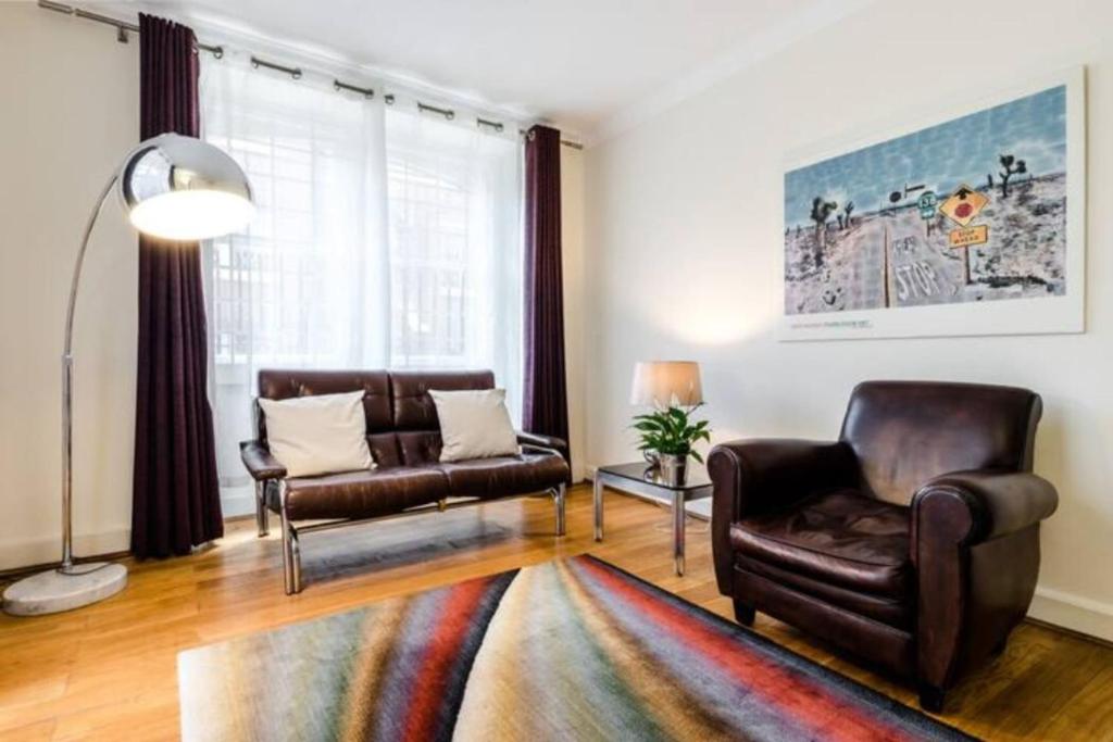 een woonkamer met lederen stoelen en een bank bij Cosy 2 Bedroom Apartment in Bayswater in Londen